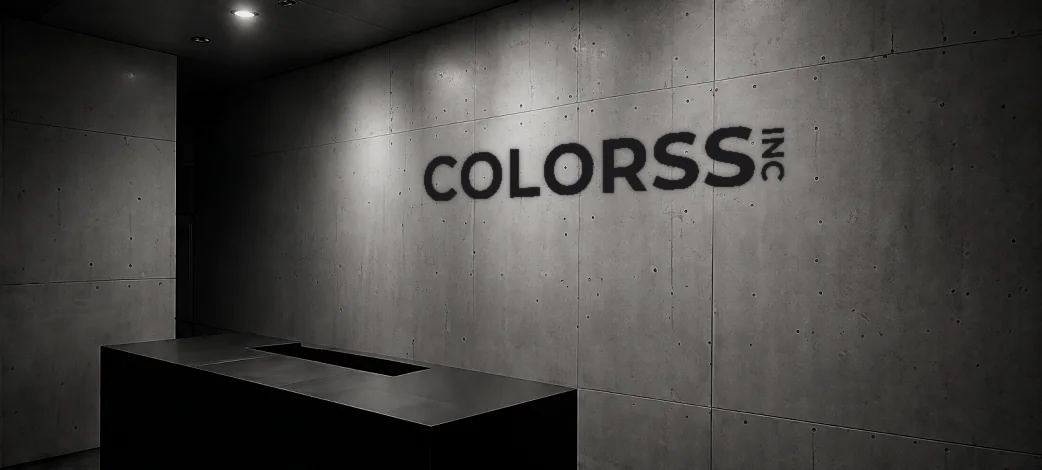 コンクリートの壁にCOLORSSのロゴが掲げられた、照明の落ちた受付